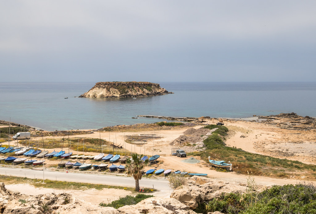 Yeronissos Island with fishing boats and dramatic coastal landscape at Agios Georgios Pegeias